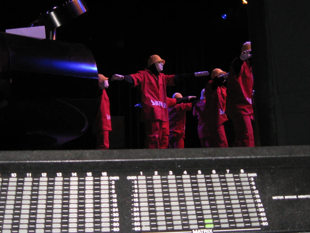 Console meter bridge in the foreground with masked dancers on stage