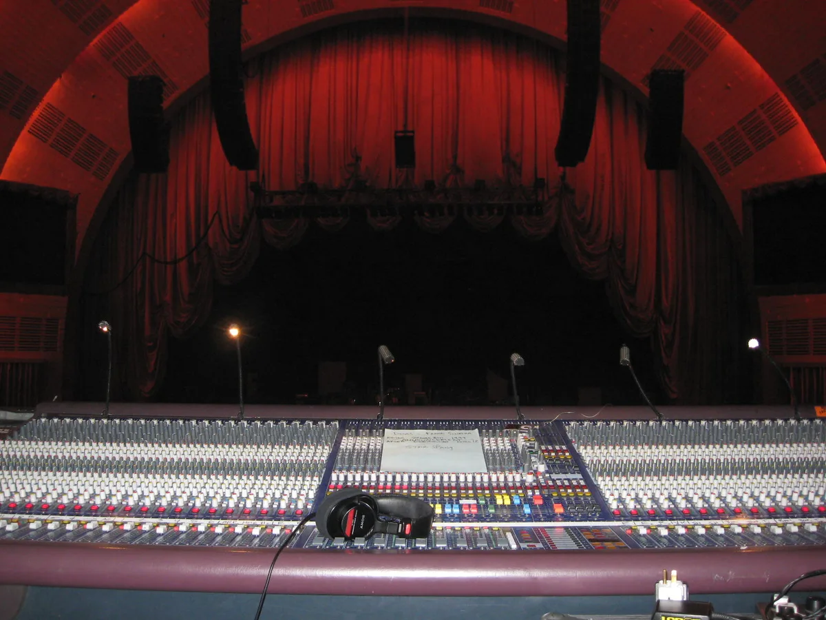 Large-format console at front of house facing a curtained proscenium stage